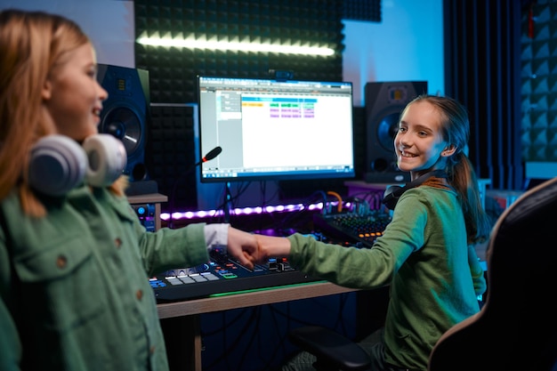 Niñas felices en la estación de radio o en el estudio de grabación, niños animándose unos a otros con un trabajo exitoso