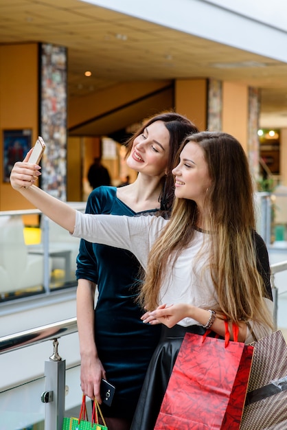 Las niñas felices están comprando en el centro comercial.