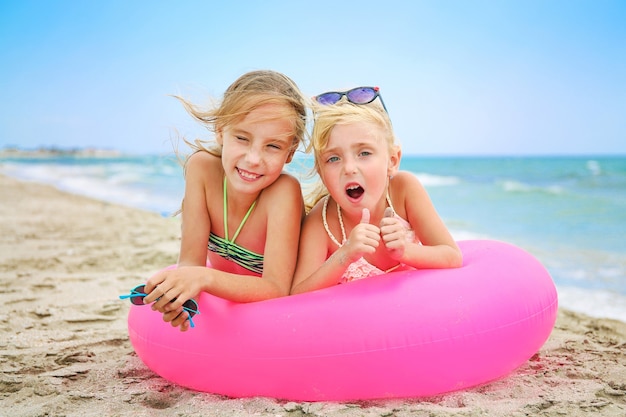 Niñas felices en inflable rosa en la playa