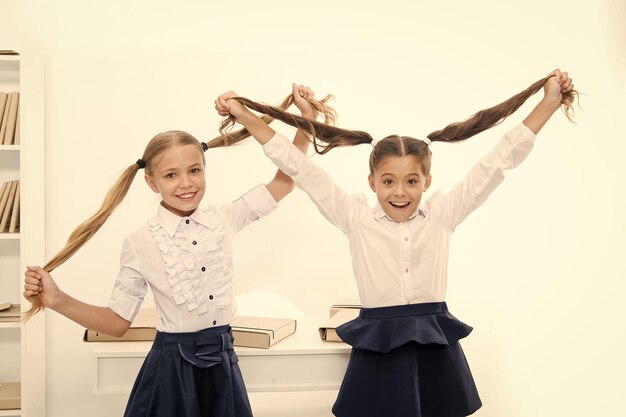 Niñas felices juegan al juego de peluquería en la escuela Niñas pequeñas se peinan como peluqueras