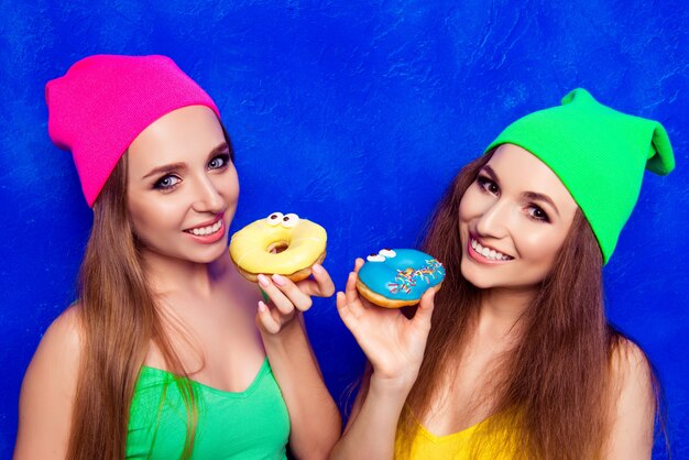 Niñas felices con sombreros con dulces donuts