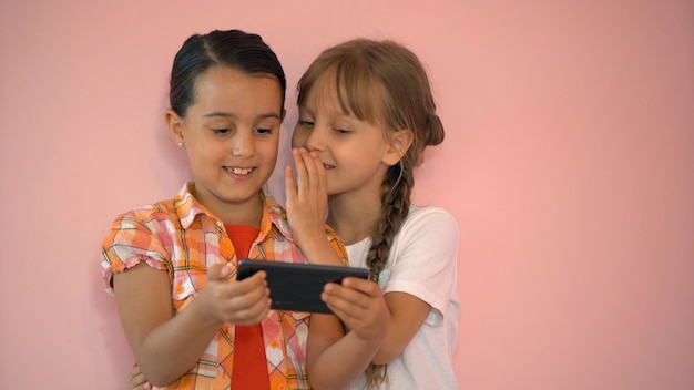 Niñas felices con un teléfono inteligente en las manos se comunican en casa con sus seres queridos usando tecnología moderna