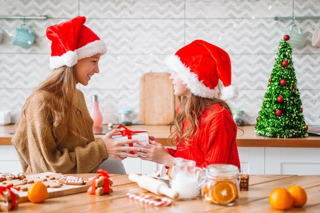 Niñas haciendo casa de pan de jengibre de Navidad en la chimenea en el salón decorado.