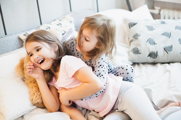 Niñas jugando en la cama en casa durante la Navidad