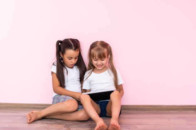 Foto niñas jugando en un dispositivo de computación de tableta en el piso