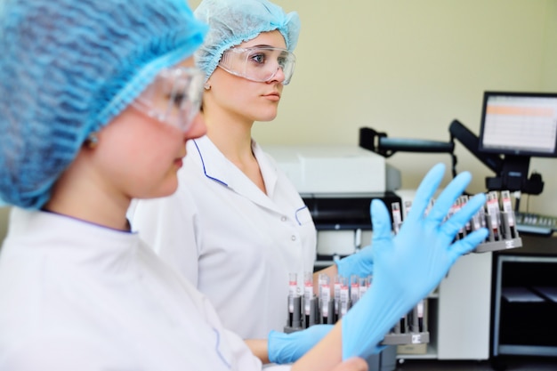 Niñas de laboratorio ponen guantes de goma.