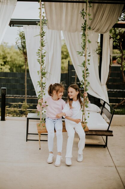 Niñas lindas en el columpio en el patio trasero de la casa