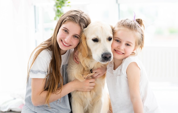 Niñas con lindo perro en habitación luminosa