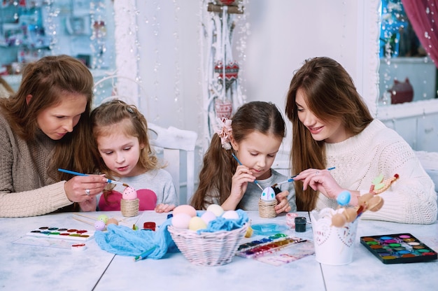 Niñas y madres pintando huevos de Pascua