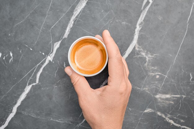 Foto niñas con la mano sosteniendo una taza de café espresso caliente en un vaso de papel para llevar