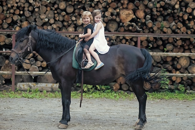 Las niñas montan a caballo el día de verano.