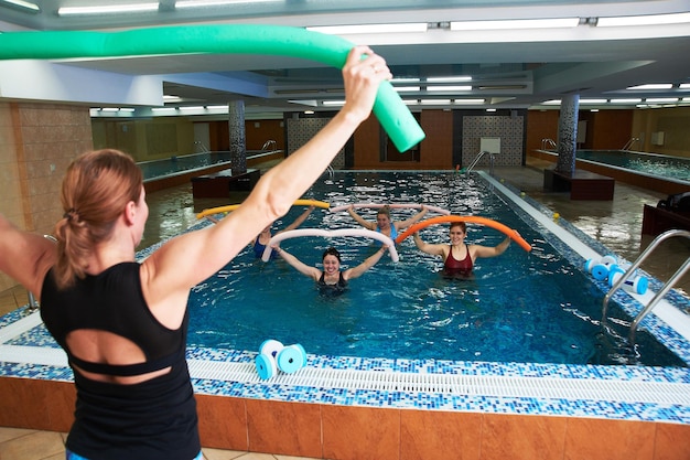 Foto niñas y mujeres adultas hacen aeróbic acuático en una piscina con un entrenador ejercicios de fitness para perder peso y bienestar en el agua