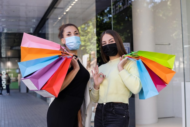 Niñas multiculturales satisfechas con máscaras protectoras de virus con bolsas coloridas