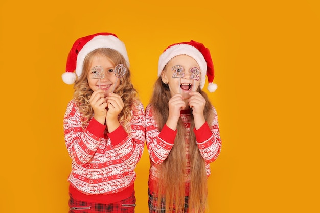 Las niñas con pantalones de puente de Año Nuevo, sombreros de Papá Noel, tienen los números 2022 en sus manos