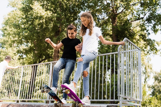 Las niñas patinadoras leen para montar en una tabla de centavos en la rampa deportiva de skate al atardecer juntos Equipo deportivo para niños Adolescente activo con pennyboard en el patio de recreo del parque de patinaje