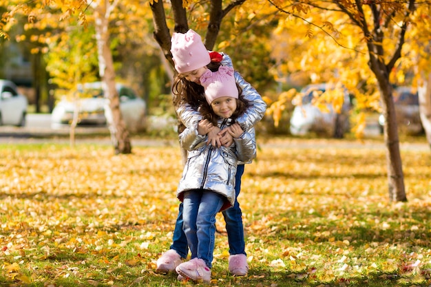 Niñas con ropa idéntica se divierten caminando en el parque de otoño