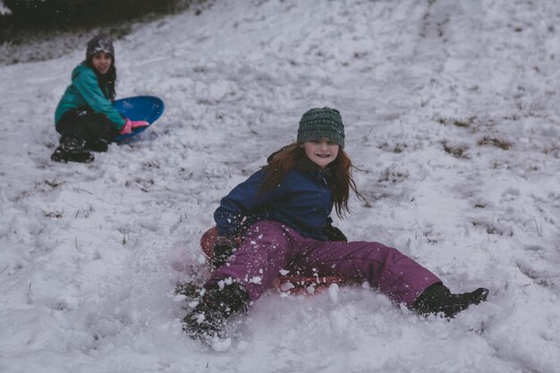 Foto niñas sentadas en trineo en la nieve.