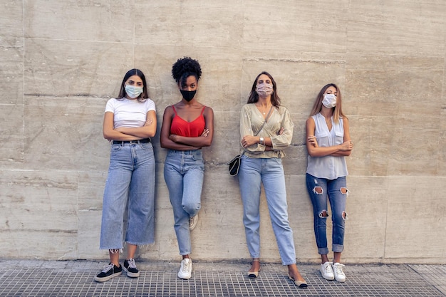 Niñas solo personas de la comunidad de pie en una pared cruzando los brazos