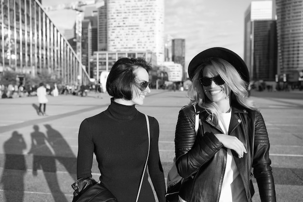 Las niñas sonríen con ropa de moda en el distrito de negocios de La Defense París Mujeres o niñas felices caminan en un día soleado en un entorno urbano Viajes de vacaciones pasión por los viajes Look de belleza de moda