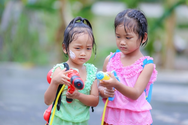 Niñas tailandesas niños jugando pistolas de agua en el festival de songkran con vestidos de época tailandesa