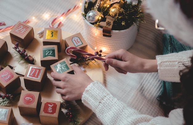 Las niñas toman una caja de calendario de adviento y sostienen una piruleta de caramelo.