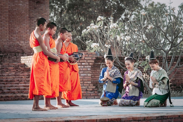 Niñas en traje nacional de Laos haciendo méritos debido al Festival Songkran y los festivales de Año Nuevo de Tailandia y Laos