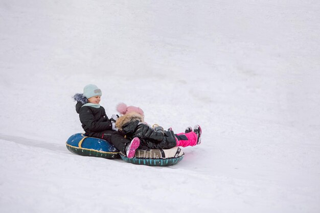 Niñas en trineo cuesta abajo a pie en un día nevado de invierno