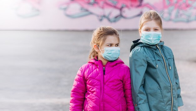Foto niñas tristes en protección médica estéril de máscara de virus al aire libre. concepto de salud, epidemia, pandemia, enfermedad