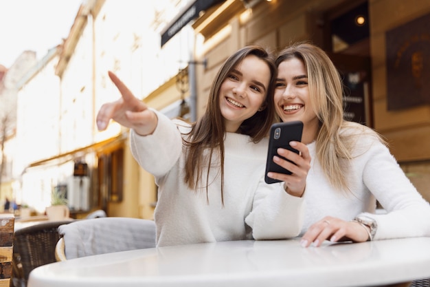 Niñas usando un teléfono inteligente en una mesa de cafetería