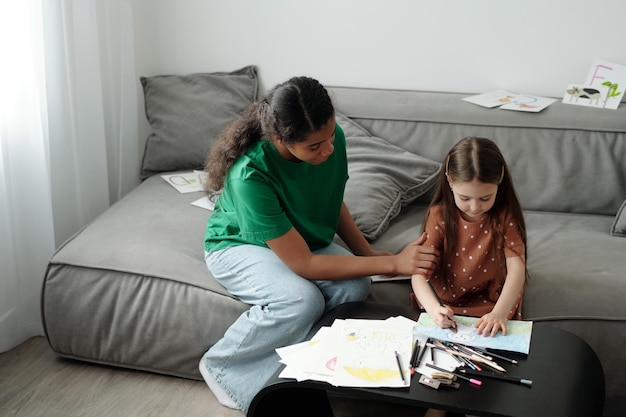 Una niñera enseñando a una niña a dibujar