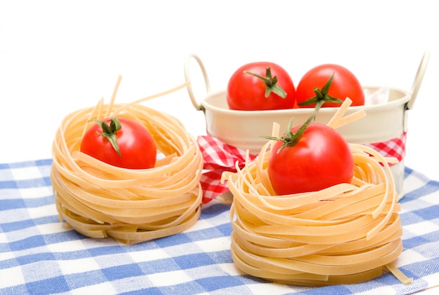 Foto ninho de macarrão e tomate vermelho cereja em guardanapo xadrez