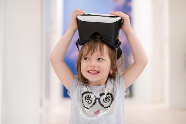 niñita en casa con gafas vr levantando las manos y jugando