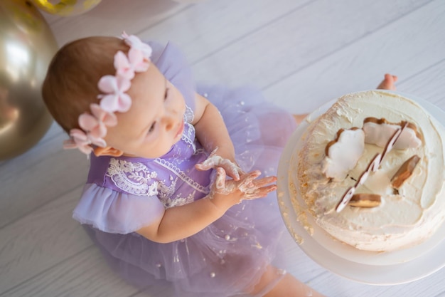 niñita en el suelo y jugando con su pastel en su primer cumpleaños Smash cake