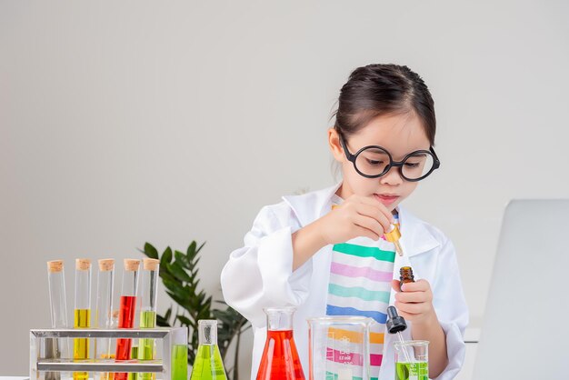 niñita Use una camisa de tierra científica trabajando con el experimento científico del tubo de ensayo en la habitación blanca