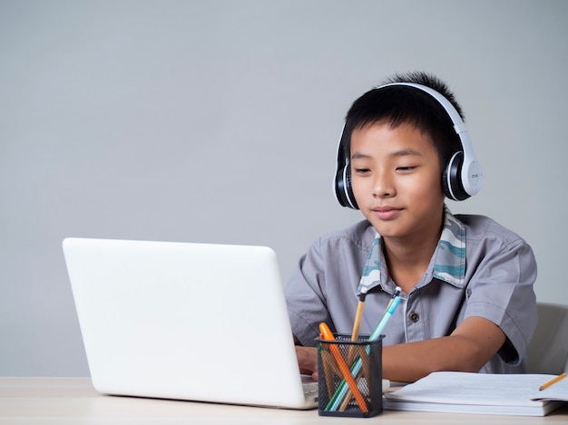 Niñito en auriculares estudiando en línea usando laptop