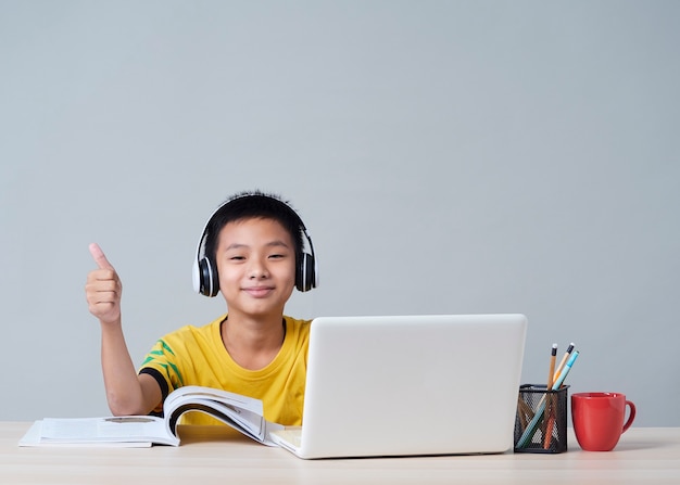 Niñito en auriculares estudiando en línea usando laptop