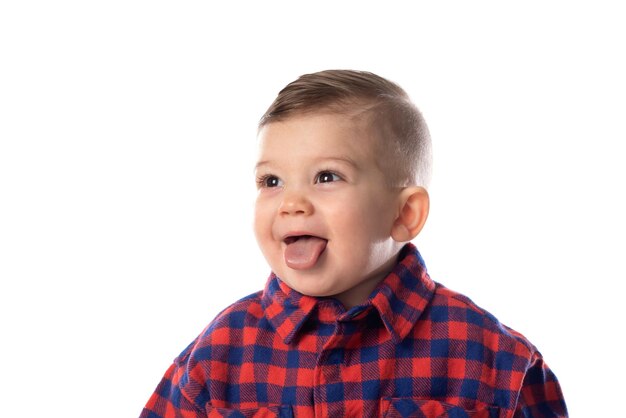 Un niñito con ropa informal elegante sonriendo sobre un fondo de pared blanca