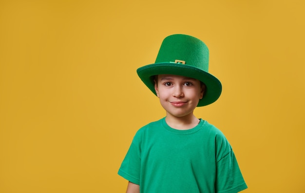 Niñito vistiendo camiseta verde y gorra irlandesa de duende mira a la cámara