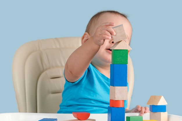 Niño de 1217 meses construyendo una torre de coloridos cubos de madera sentados en una silla