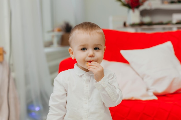 Un niño de 2 años que ríe se pone de pie y come un bagel.