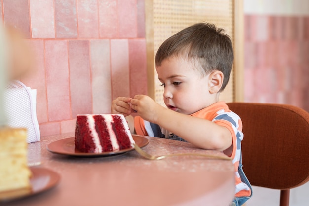 Un niño de 23 años se sienta en un café y come un pastel.