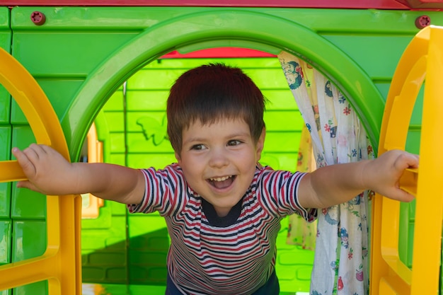 Un niño de 3 años abre una ventana, juega en una casa de juguete