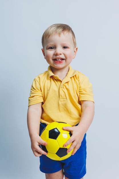 Niño de 34 años fanático del fútbol en una camiseta amarilla con una pelota en sus manos sosteniendo una pelota de fútbol en sus manos aislada en un fondo blanco El concepto de recreación familiar deportiva