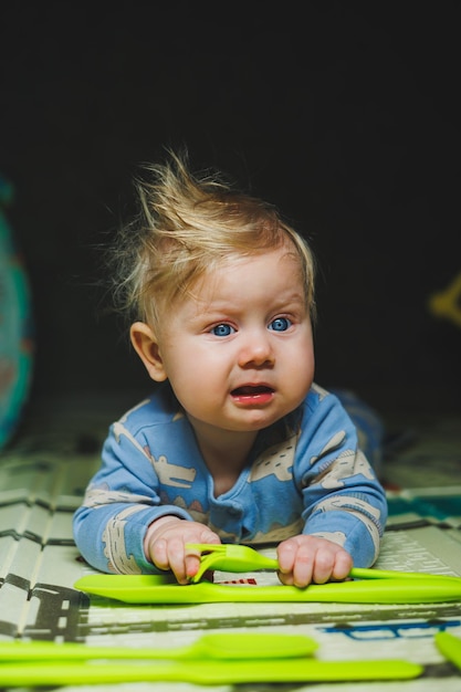 Un niño de 5 meses de edad se acuesta en una alfombra y juega con juguetes de silicona