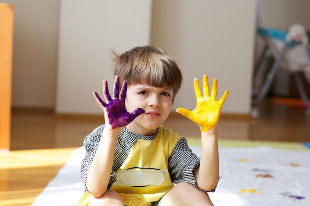 Foto niño de 6 años está pintando una manta blanca con las palmas