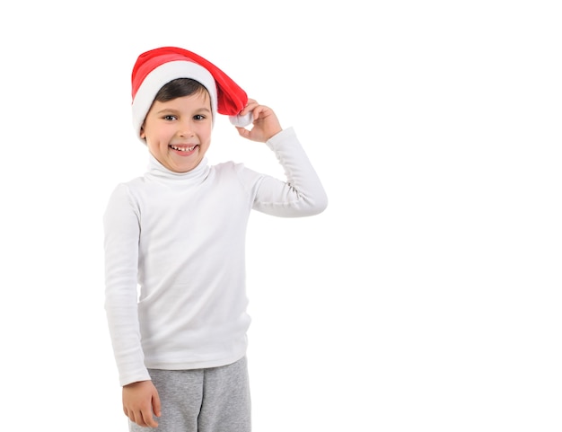 Niño de 6 años con sombrero rojo de santa claus y suéter blanco sobre fondo blanco aislado año nuevo Chris