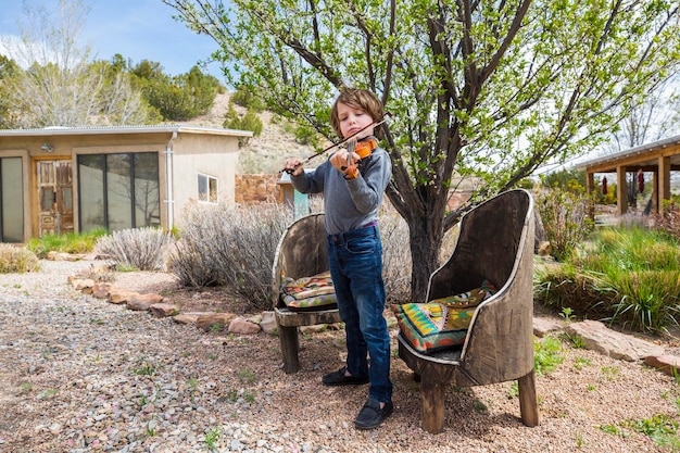 Niño de 6 años tocando el violín fuera de su casa