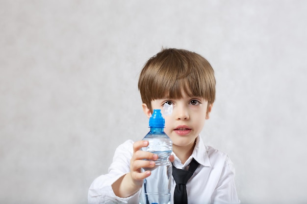 Foto niño de 6 años vestido con camisa blanca está bebiendo agua