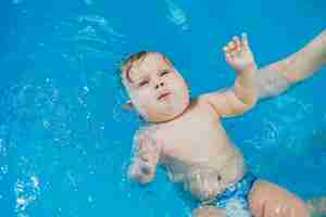 Foto un niño de 7 meses está aprendiendo a nadar en la piscina con un entrenador lecciones de natación para niños