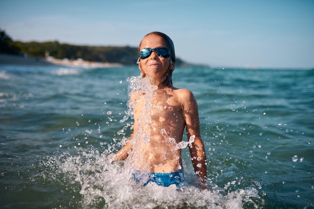 Niño de 8 años nada en el mar con gafas de natación azules por la noche